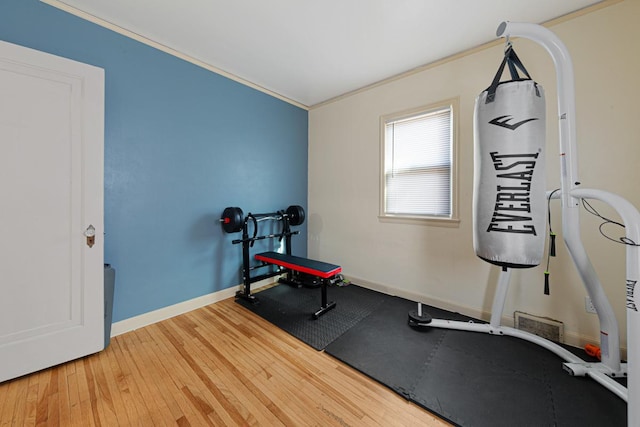 exercise area featuring crown molding, baseboards, and wood-type flooring