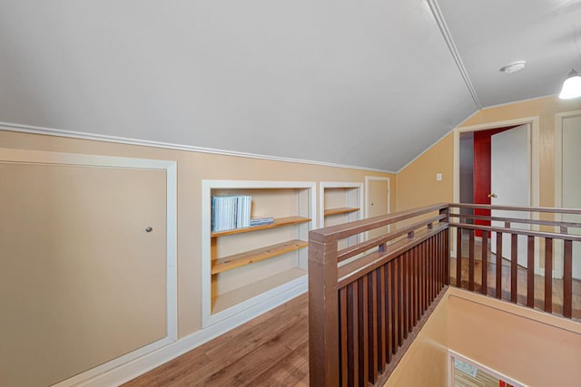 hall featuring an upstairs landing, built in features, lofted ceiling, and wood finished floors