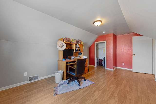 office area featuring visible vents, baseboards, lofted ceiling, and wood finished floors