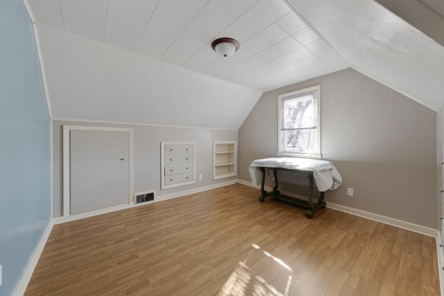 bonus room featuring visible vents, light wood-type flooring, built in features, baseboards, and vaulted ceiling