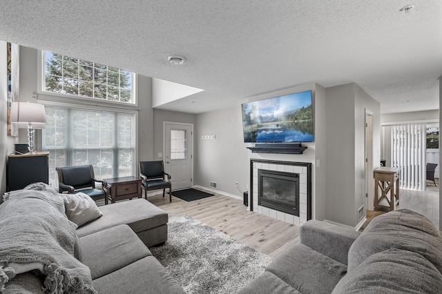 living area with a textured ceiling, a fireplace, wood finished floors, and baseboards