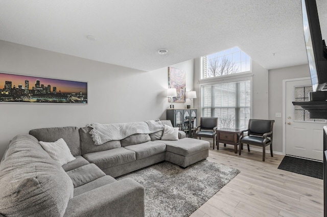 living area featuring a textured ceiling, light wood-style flooring, and baseboards