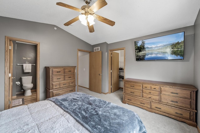 carpeted bedroom featuring vaulted ceiling, connected bathroom, visible vents, and a ceiling fan