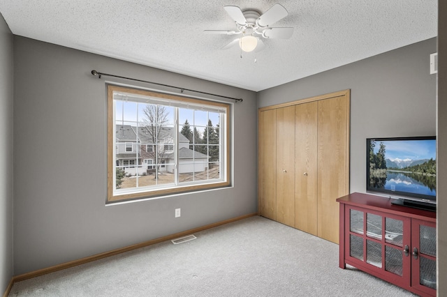 unfurnished bedroom with carpet, a closet, visible vents, a textured ceiling, and baseboards