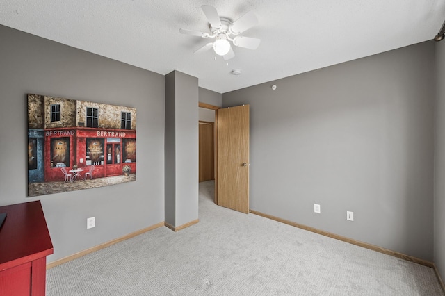 carpeted empty room featuring a ceiling fan and baseboards