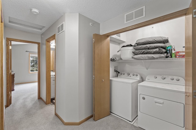 laundry area featuring washing machine and dryer, visible vents, and light colored carpet