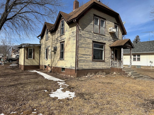 view of side of home with cooling unit and a chimney