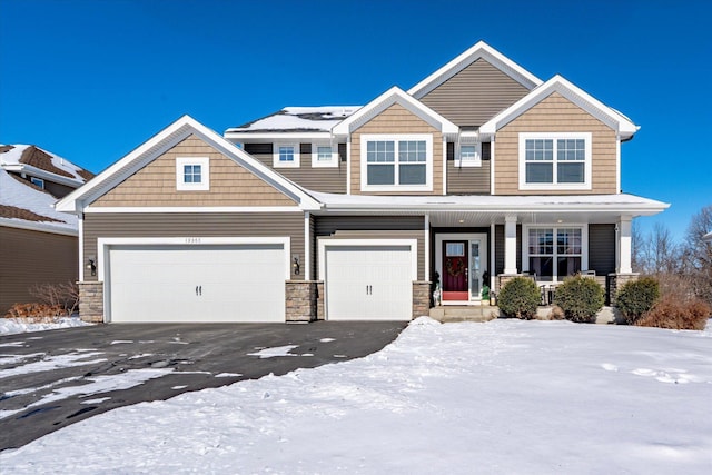 craftsman house featuring covered porch, stone siding, and aphalt driveway