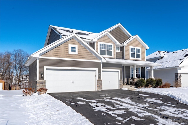 craftsman-style home featuring stone siding, covered porch, driveway, and a garage