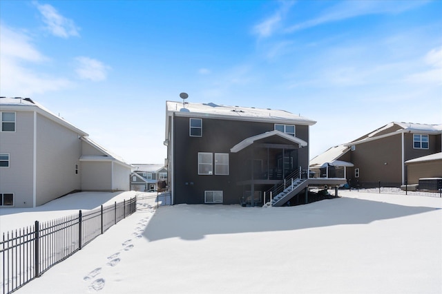 snow covered property featuring a fenced backyard, stairs, and central AC unit