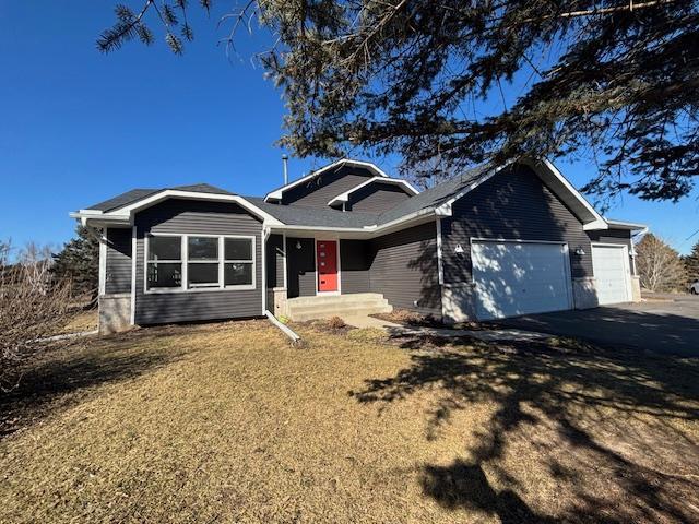 ranch-style home with aphalt driveway, an attached garage, and a front yard