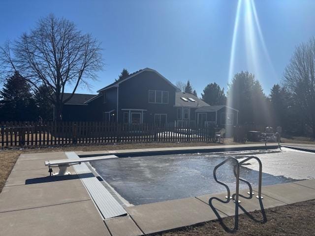 view of swimming pool featuring fence and a diving board