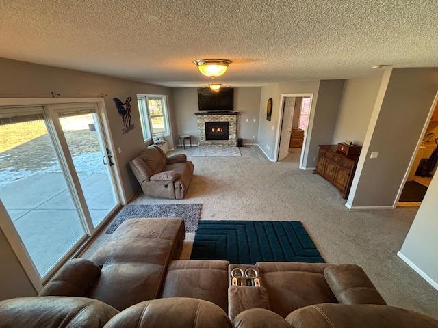 living area with baseboards, a lit fireplace, a textured ceiling, and light colored carpet