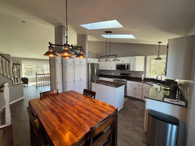 dining space with vaulted ceiling with skylight and stairway