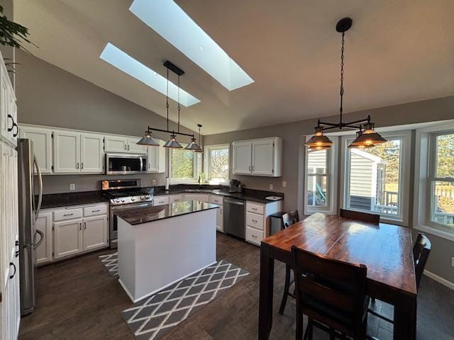 kitchen with stainless steel appliances, a skylight, white cabinetry, a center island, and dark countertops