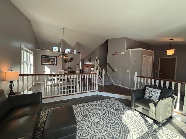 living room with vaulted ceiling, wood finished floors, stairs, and visible vents