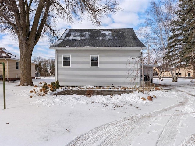 view of snowy exterior with a shingled roof