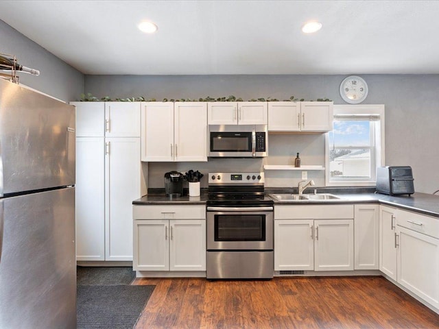 kitchen featuring white cabinets, dark wood-type flooring, stainless steel appliances, and a sink