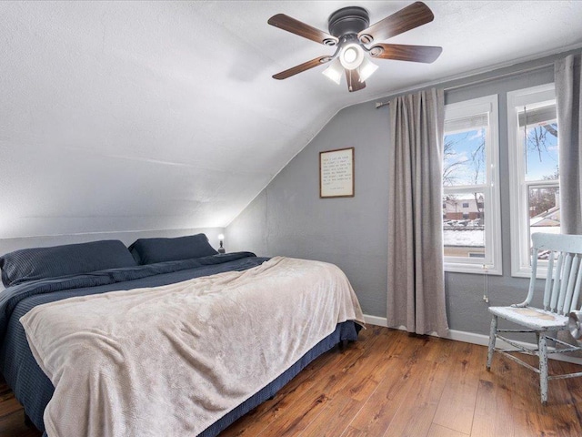 bedroom with vaulted ceiling, hardwood / wood-style floors, a ceiling fan, and baseboards