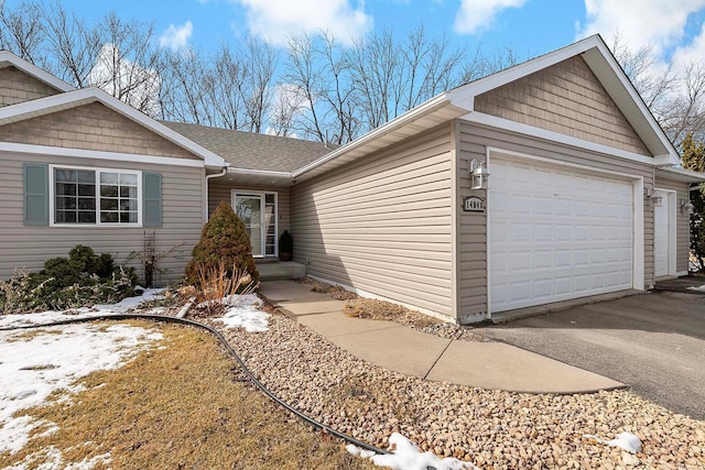 single story home with aphalt driveway, a garage, and roof with shingles