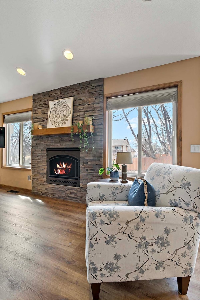 living area with visible vents, recessed lighting, a fireplace, and wood finished floors