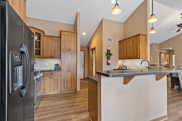 kitchen featuring dark countertops, visible vents, stainless steel range with gas cooktop, lofted ceiling, and black refrigerator with ice dispenser