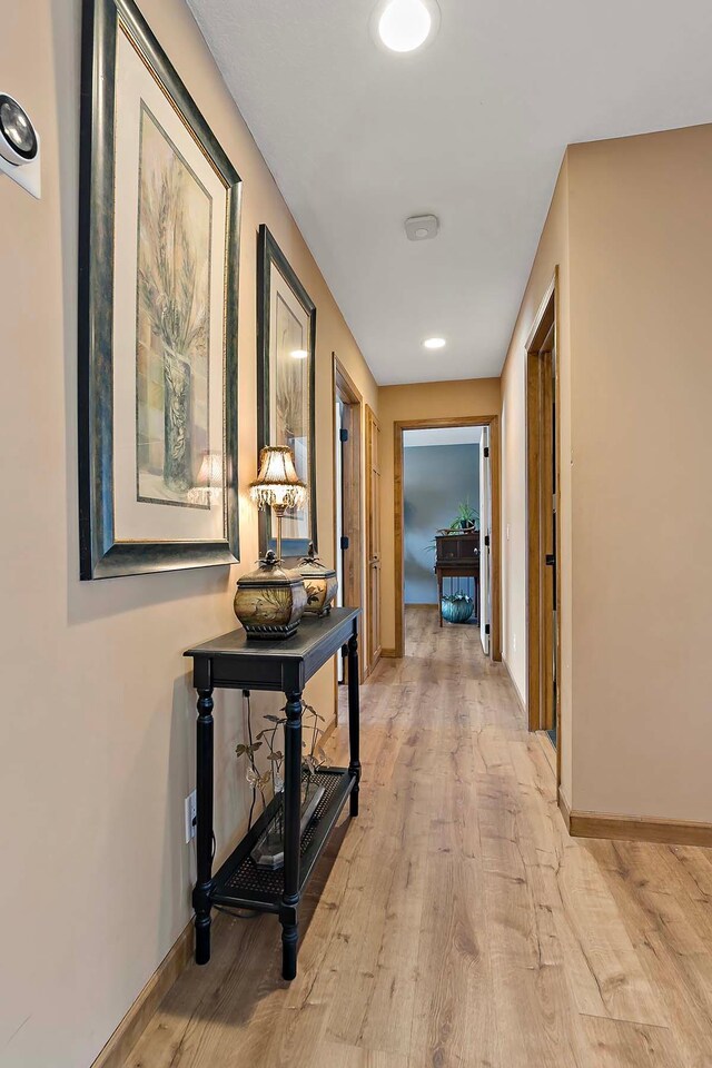 hallway featuring baseboards and light wood-type flooring