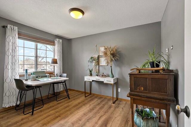 home office with a textured ceiling, baseboards, and wood finished floors