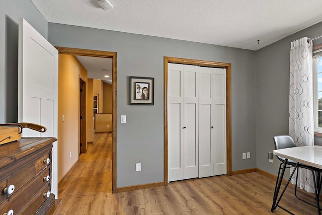 home office with baseboards, a textured ceiling, and light wood-style floors