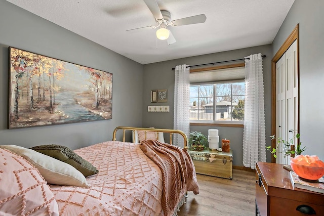 bedroom with a ceiling fan, wood finished floors, and a textured ceiling