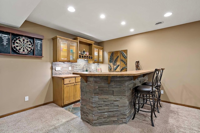 bar with decorative backsplash, visible vents, dark colored carpet, and indoor wet bar