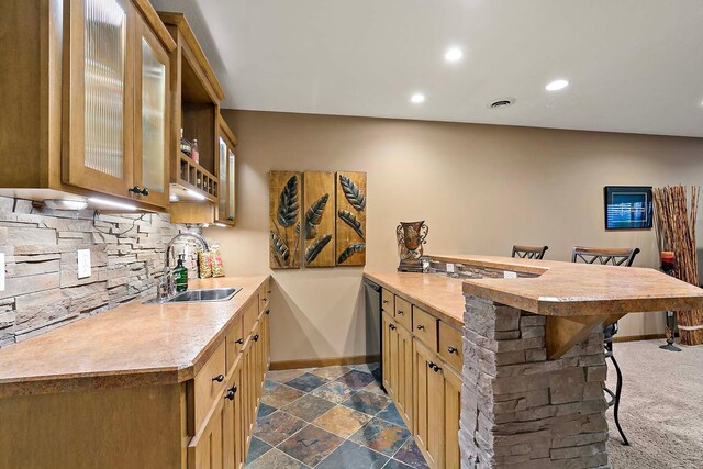 kitchen with a sink, a kitchen breakfast bar, backsplash, a peninsula, and light countertops