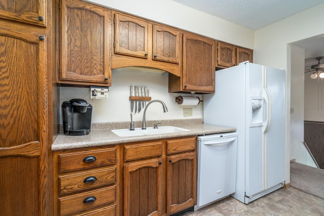 kitchen featuring light countertops, white appliances, brown cabinetry, and a sink