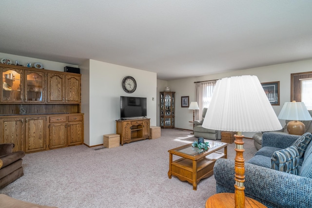 living room with a healthy amount of sunlight, light carpet, and baseboards