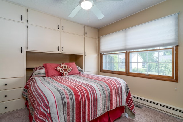 bedroom featuring a textured ceiling, baseboard heating, carpet flooring, and a ceiling fan