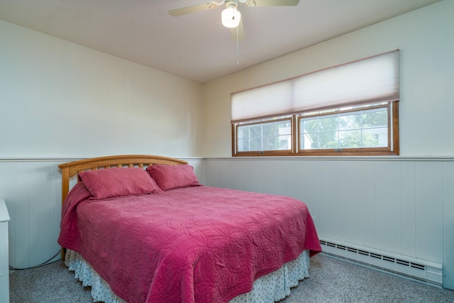 bedroom featuring a baseboard heating unit, a wainscoted wall, and a ceiling fan