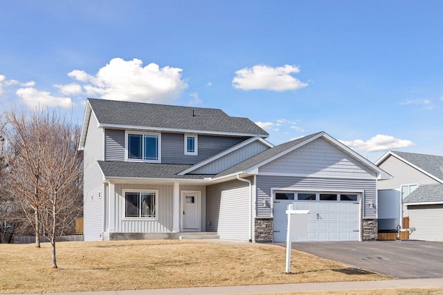 view of front facade with a garage, aphalt driveway, a shingled roof, and a front yard