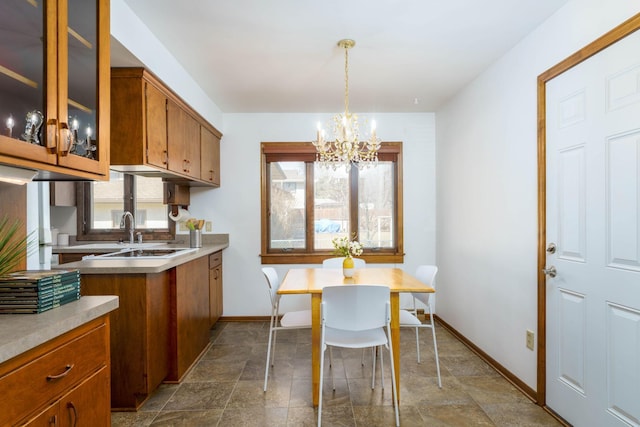 kitchen featuring light countertops, brown cabinetry, a wealth of natural light, and a chandelier