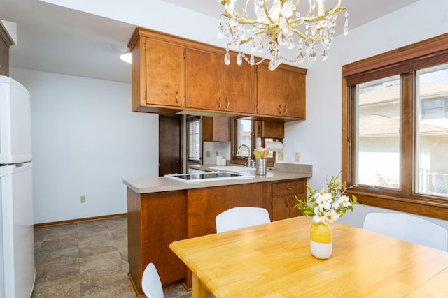 kitchen with brown cabinetry, white appliances, baseboards, and a wealth of natural light