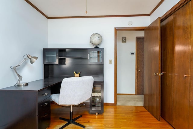 office area featuring baseboards, light wood-style floors, and crown molding