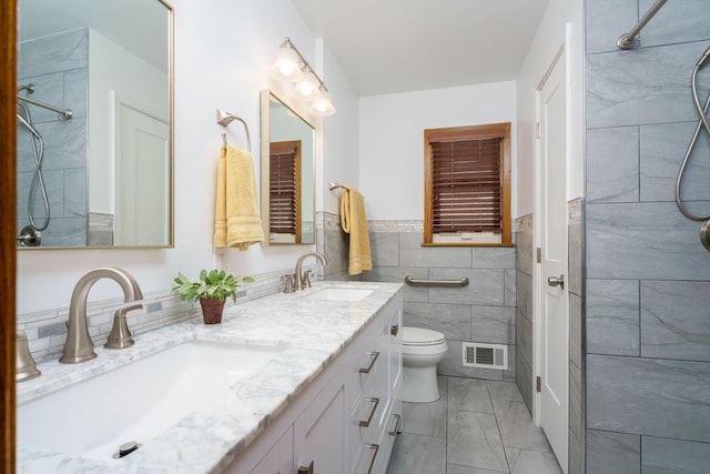 bathroom featuring a tile shower, visible vents, tile walls, and a sink