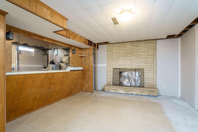 unfurnished living room with tile patterned floors, electric panel, a brick fireplace, and wooden walls