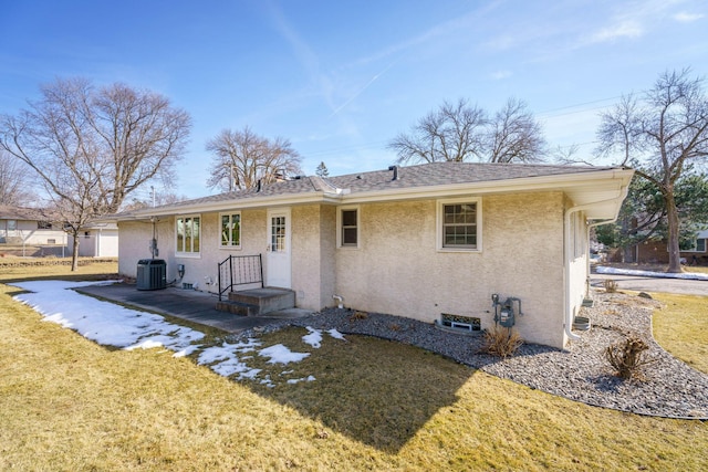 view of front of home with a shingled roof, a front yard, cooling unit, and stucco siding