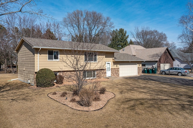 view of front facade with driveway, an attached garage, a front lawn, and a shingled roof