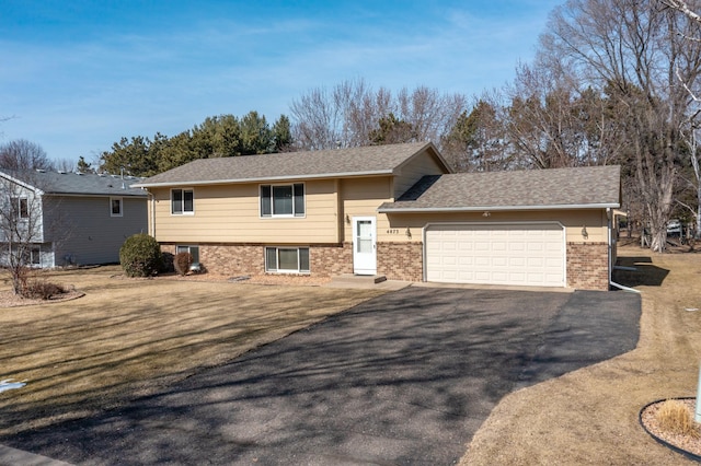 view of front facade with brick siding, a front lawn, aphalt driveway, roof with shingles, and an attached garage