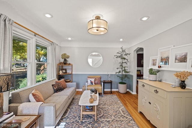 living room featuring light wood finished floors, baseboards, arched walkways, and recessed lighting