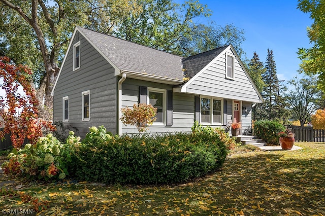 view of front of house featuring a front lawn, roof with shingles, and fence