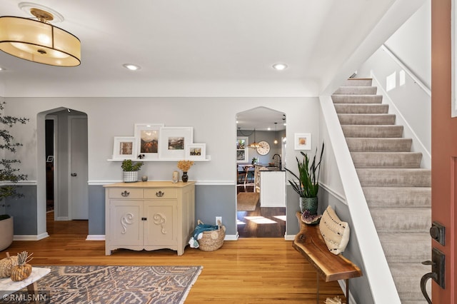 foyer featuring light wood-style floors, arched walkways, stairway, and recessed lighting