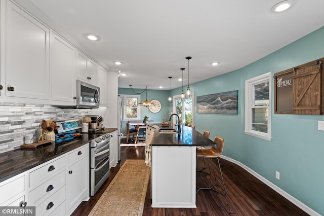 kitchen with dark countertops, tasteful backsplash, stainless steel appliances, and a sink