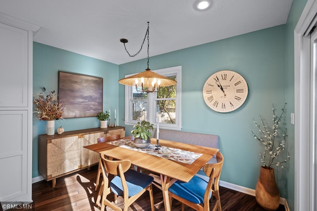 dining space featuring dark wood-style floors, a notable chandelier, and baseboards